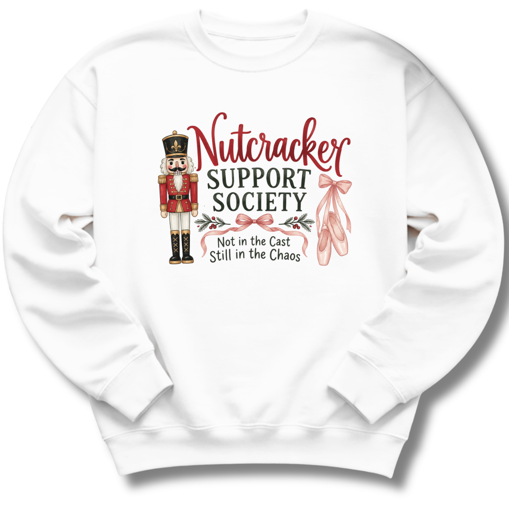 A white crewneck sweatshirt featuring a 'Nutcracker Support Society' graphic on the chest, complete with a nutcracker illustration, red script text, and pink ballet slippers.