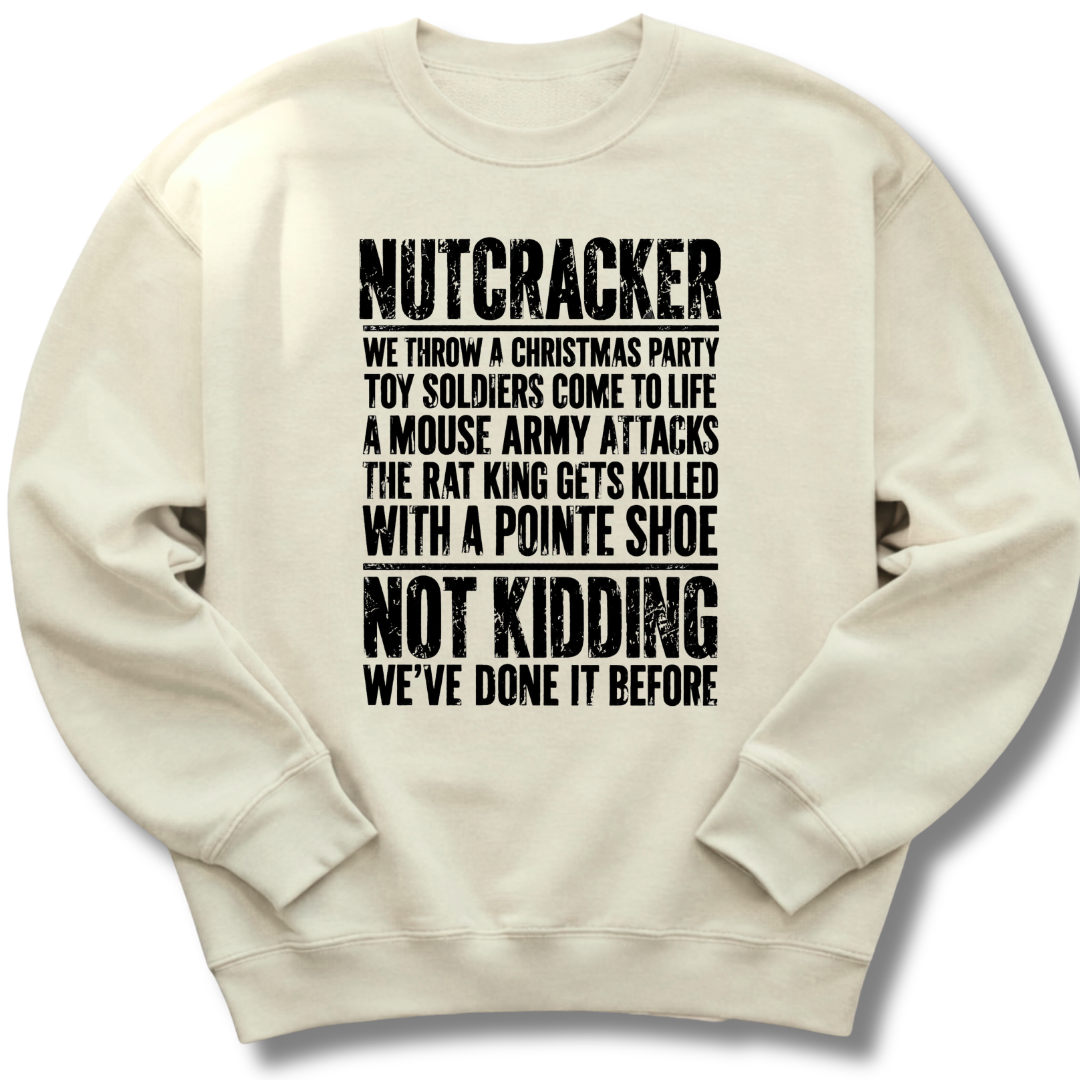 An off-white crewneck sweatshirt with black distressed text on the front that reads 'NUTCRACKER WE THROW A CHRISTMAS PARTY TOY SOLDIERS COME TO LIFE A MOUSE ARMY ATTACKS THE RAT KING GETS KILLED WITH A POINTE SHOE NOT KIDDING WE'VE DONE IT BEFORE.'.