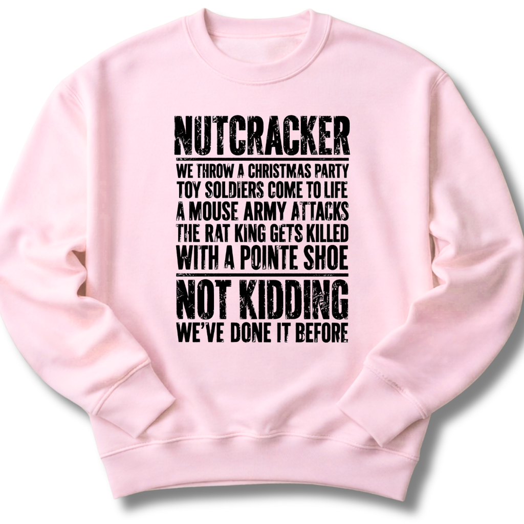 A light pink crewneck sweatshirt with a black distressed text graphic on the front that reads 'NUTCRACKER' followed by a humorous Christmas-themed story and 'NOT KIDDING WE'VE DONE IT BEFORE.'.