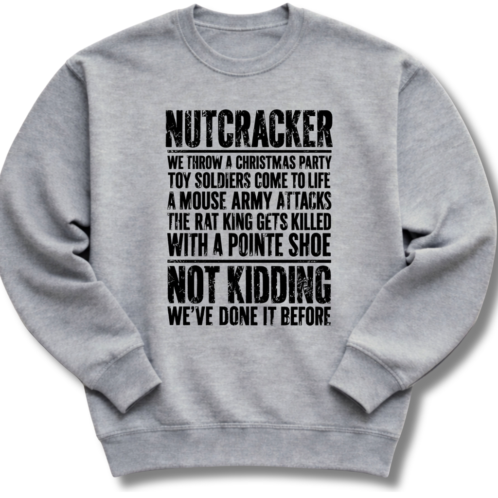 A light gray crewneck sweatshirt with black distressed text on the front that reads 'NUTCRACKER WE THROW A CHRISTMAS PARTY TOY SOLDIERS COME TO LIFE A MOUSE ARMY ATTACKS THE RAT KING GETS KILLED WITH A POINTE SHOE NOT KIDDING WE'VE DONE IT BEFORE.'.