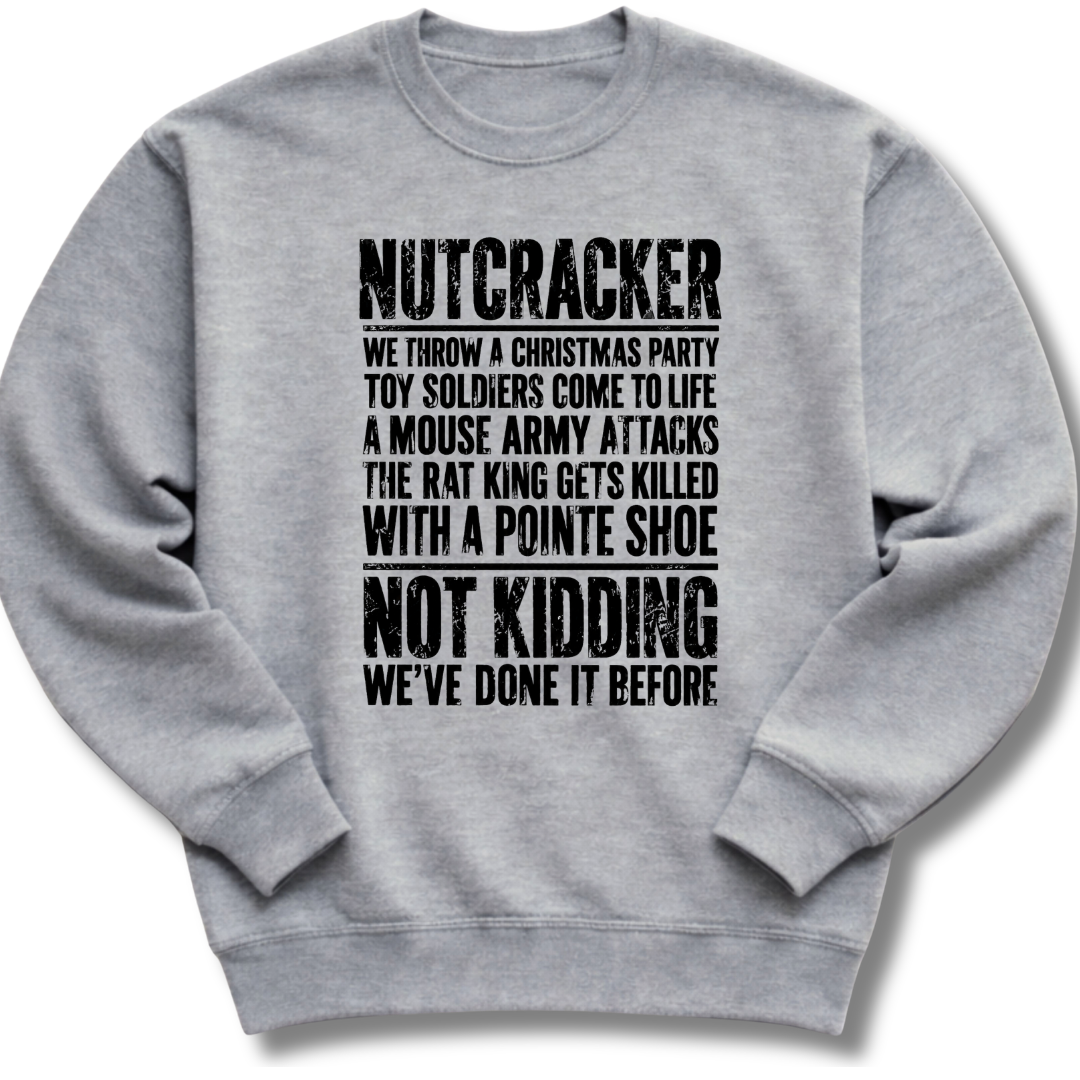 A light gray crewneck sweatshirt with black distressed text on the front that reads 'NUTCRACKER WE THROW A CHRISTMAS PARTY TOY SOLDIERS COME TO LIFE A MOUSE ARMY ATTACKS THE RAT KING GETS KILLED WITH A POINTE SHOE NOT KIDDING WE'VE DONE IT BEFORE.'.