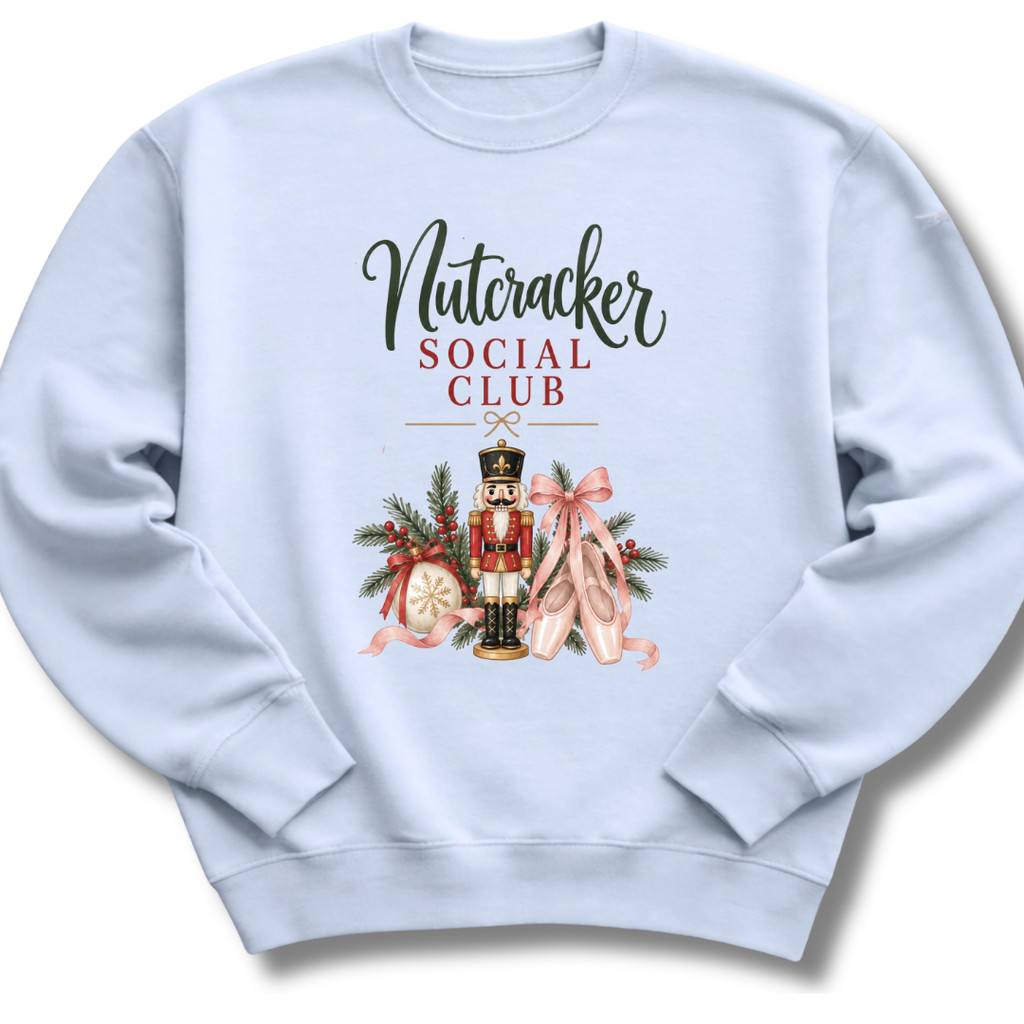 A light blue crewneck sweatshirt featuring a 'Nutcracker Social Club' graphic on the chest with a nutcracker, pink ballet slippers, and holiday decorations.