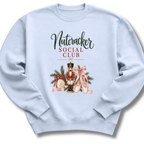 A light blue crewneck sweatshirt featuring a 'Nutcracker Social Club' graphic on the chest with a nutcracker, pink ballet slippers, and holiday decorations.