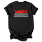 A black short-sleeve t-shirt with a humorous warning graphic printed on the chest. The graphic features the word 'WARNING' in bold red letters, followed by white text explaining that the dance skills shown in the shirt are performed by a trained professional.