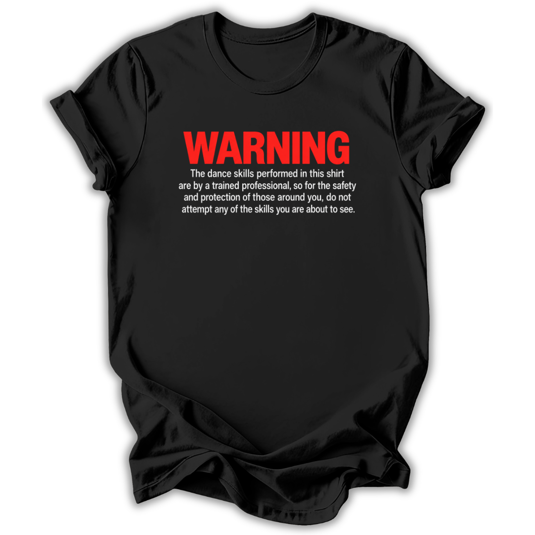A black short-sleeve t-shirt with a humorous warning graphic printed on the chest. The graphic features the word 'WARNING' in bold red letters, followed by white text explaining that the dance skills shown in the shirt are performed by a trained professional.