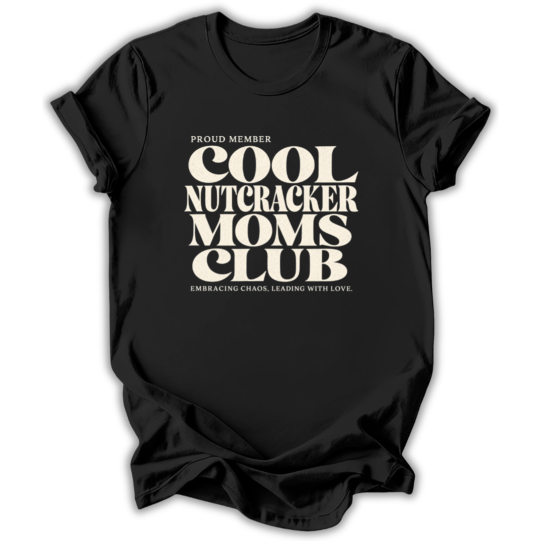 Black short-sleeve crewneck t-shirt with a cream-colored retro graphic that reads 'PROUD MEMBER COOL NUTCRACKER MOMS CLUB' and 'EMBRACING CHANGE, LEADING WITH LOVE.'.