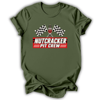 An olive green short-sleeve t-shirt with a 'Nutcracker Pit Crew' graphic on the chest, featuring a race flag checkered pattern and a pit crew character, displayed on a clean white background.