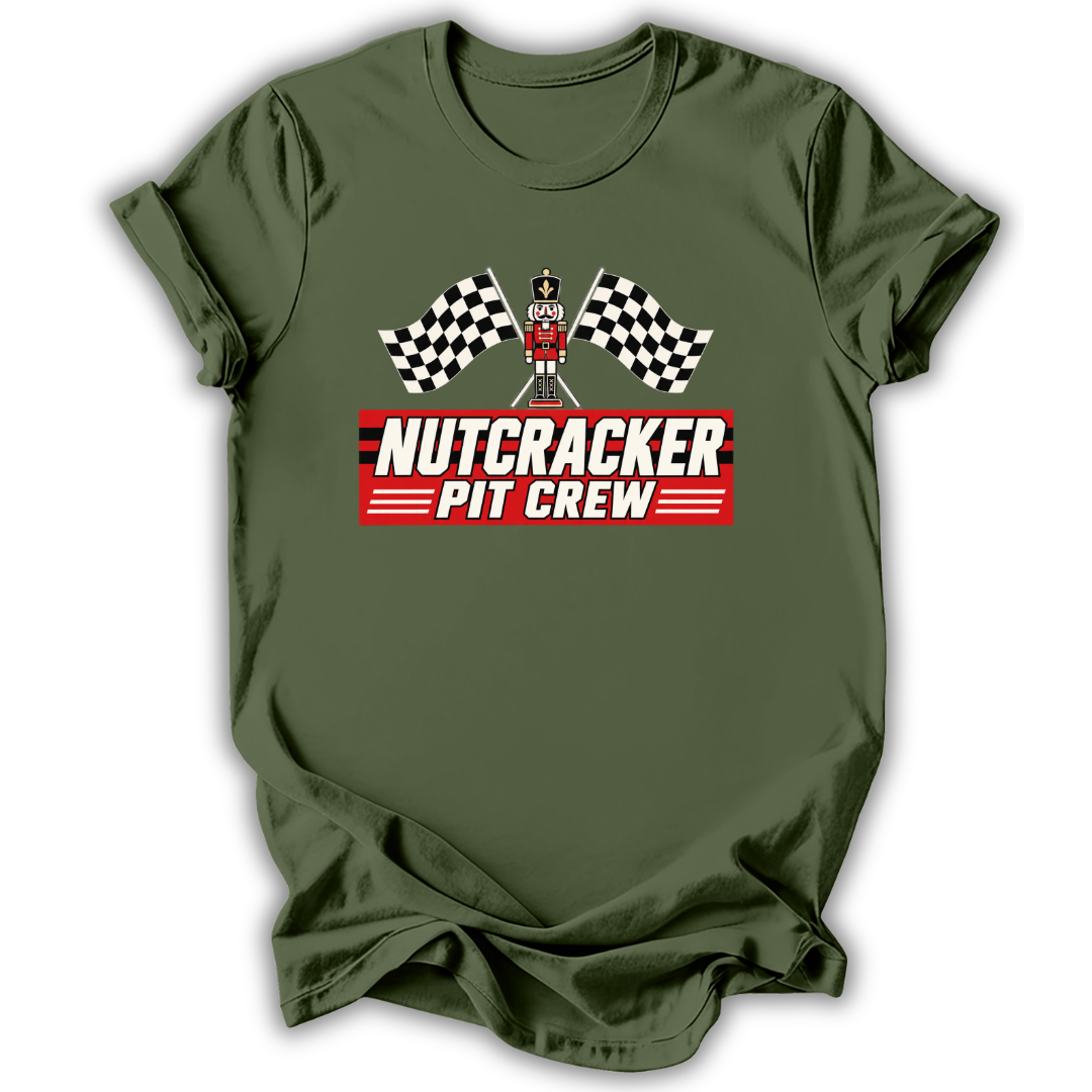 An olive green short-sleeve t-shirt with a 'Nutcracker Pit Crew' graphic on the chest, featuring a race flag checkered pattern and a pit crew character, displayed on a clean white background.