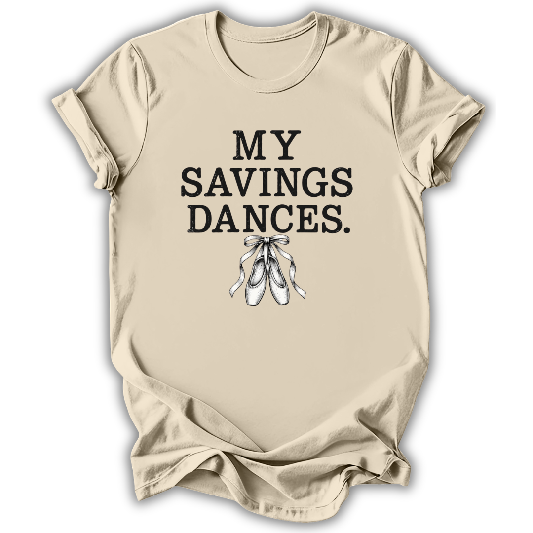 A beige short-sleeve t-shirt with the text 'MY SAVINGS DANCES.' printed in black, accompanied by a graphic of white ballet pointe shoes, shown on a white background.