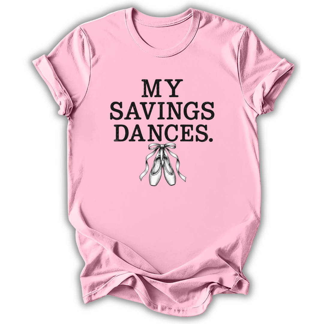 A light pink short-sleeve t-shirt with the text 'MY SAVINGS DANCES.' printed in black block letters above a graphic of white ballet slippers, shown on a white background with a drop shadow.