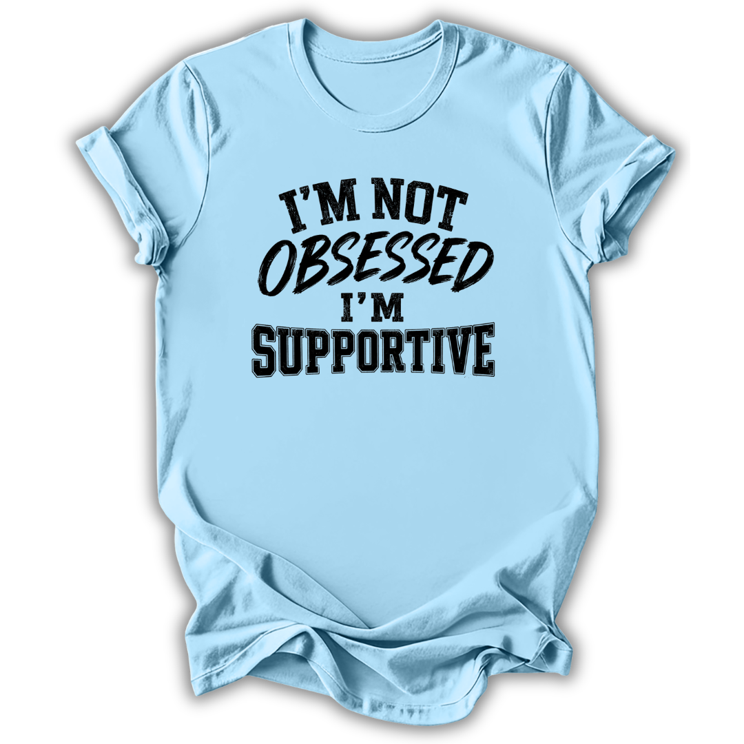 A light blue short-sleeve t-shirt with the text 'I'M NOT OBSESSED I'M SUPPORTIVE' printed in black across the chest, shown on a plain white background.