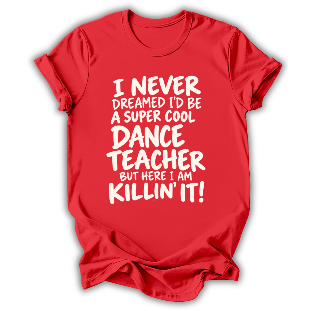 A red short-sleeve t-shirt with white text on the front that reads, 'I NEVER DREAMED I'D BE A SUPER COOL DANCE TEACHER BUT HERE I AM KILLIN' IT!' shown on a white background.