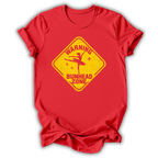 A red short-sleeve crewneck t-shirt with a yellow diamond-shaped graphic on the chest. The graphic features a silhouette of a ballerina and the text 'WARNING BUNHEAD ZONE' in a distressed, vintage style.
