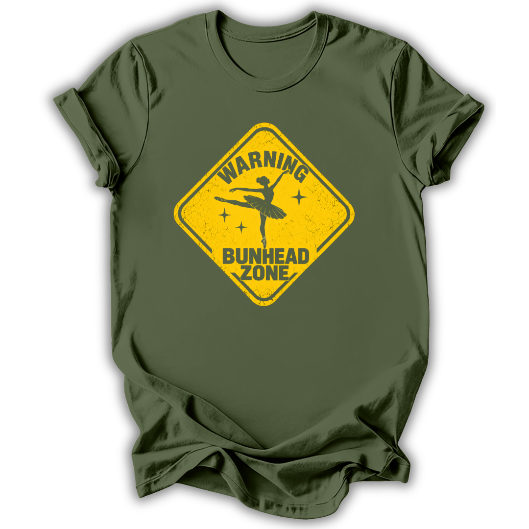 An olive green short-sleeve t-shirt with a yellow diamond-shaped road sign graphic on the chest that reads 'WARNING BUNHEAD ZONE' with a silhouette of a ballerina.