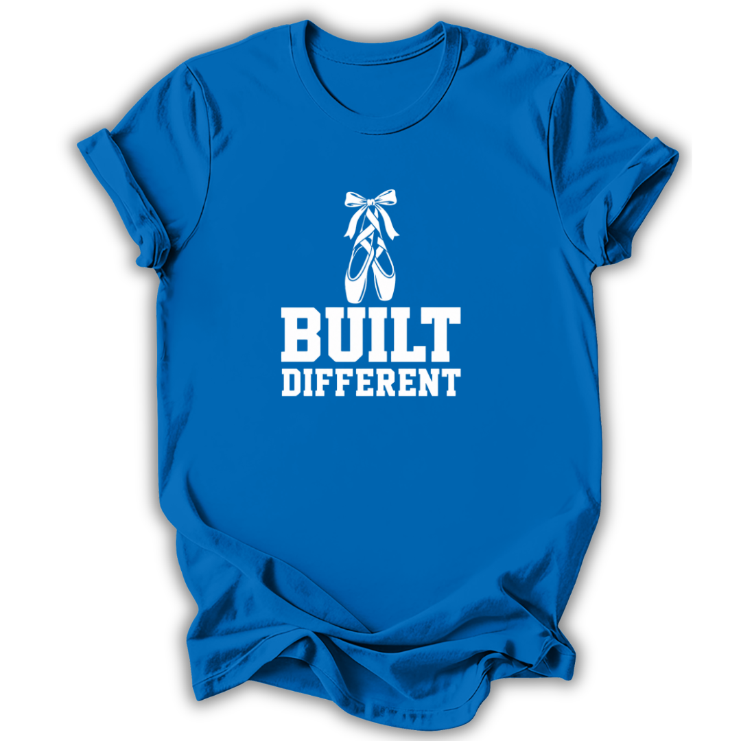 A royal blue short-sleeve t-shirt with a white graphic print featuring a pair of pointe shoes and the text 'BUILT DIFFERENT'.