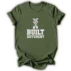 An olive green short-sleeve t-shirt with a white graphic print featuring a ballet pointe shoe and the text 'BUILT DIFFERENT'.