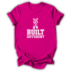 A bright pink short-sleeve t-shirt with a white graphic print featuring ballet slippers and the text 'BUILT DIFFERENT'.