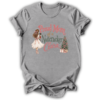 A heather gray short-sleeve t-shirt with a graphic print on the front. The print features an illustration of a woman in a white dress holding a nutcracker, next to the text 'Proud Mom of a Nutcracker Clara' in coral and green lettering, with a small decorated Christmas tree and wrapped gifts.