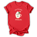 A red short-sleeve t-shirt with a holiday graphic on the front. The graphic features a white mug filled with hot chocolate, topped with whipped cream, a candy cane, and a green Christmas tree, with the text 'Hot Chocolate' above and 'The Nutacker' below.