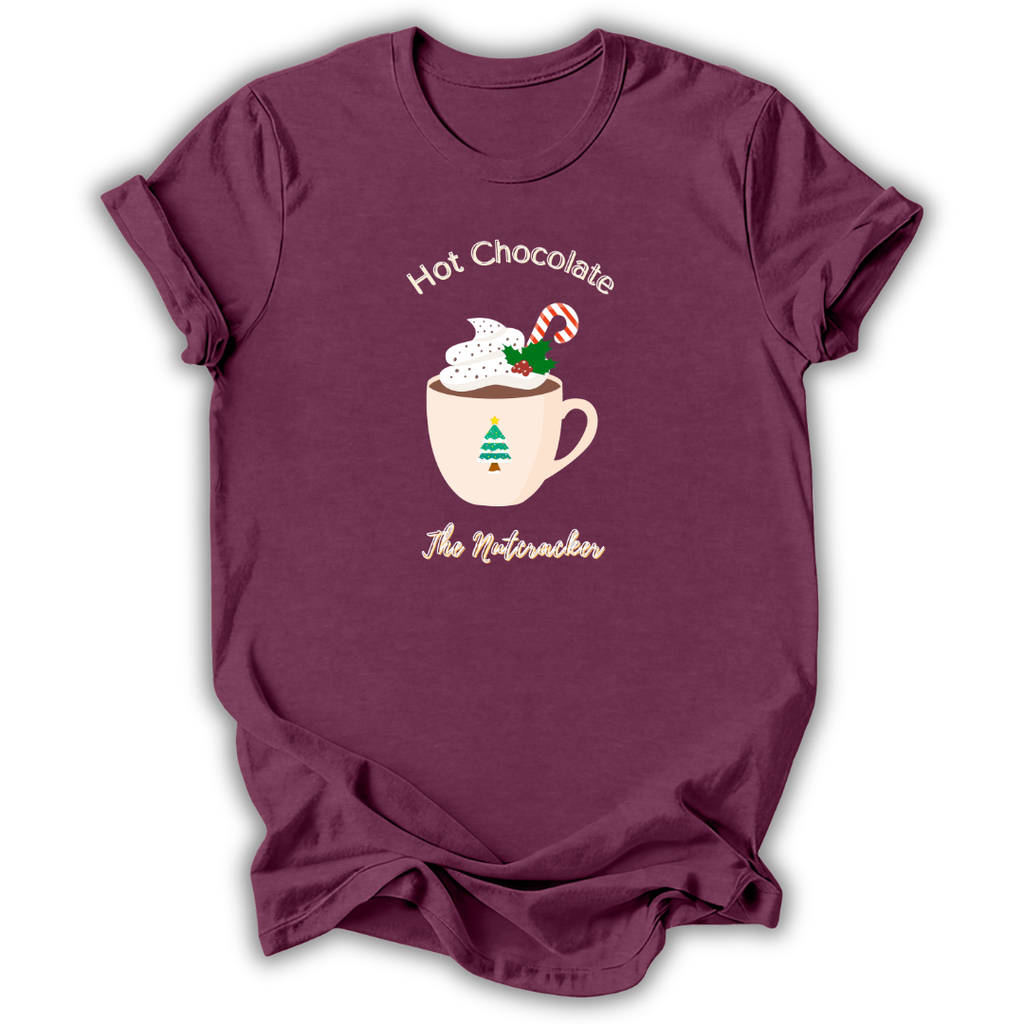 A maroon short-sleeve t-shirt with a holiday graphic on the front. The graphic shows a mug filled with hot chocolate and whipped cream, decorated with a candy cane and green sprig, with the text 'Hot Chocolate' above and 'The Nutacker' below.