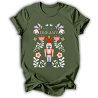 An olive green short-sleeve t-shirt with a colorful graphic of a nutcracker surrounded by flowers and the text 'WAS IT A DREAM?'.