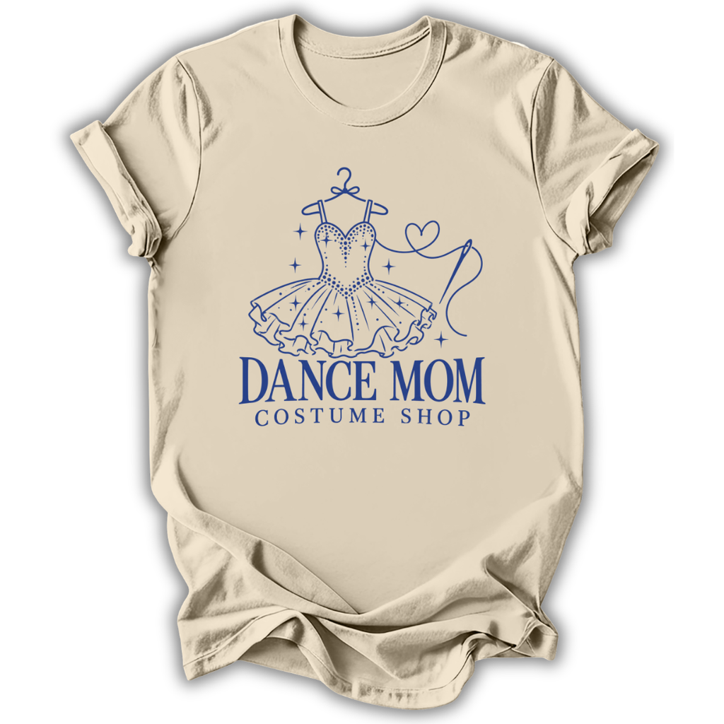 A beige short-sleeve t-shirt with a blue graphic of a ballroom dance tutu on a hanger and the text 'DANCE MOM COSTUME SHOP' printed on the front, displayed against a white background.