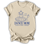 A beige short-sleeve t-shirt with a blue graphic of a ballroom dance tutu on a hanger and the text 'DANCE MOM COSTUME SHOP' printed on the front, displayed against a white background.
