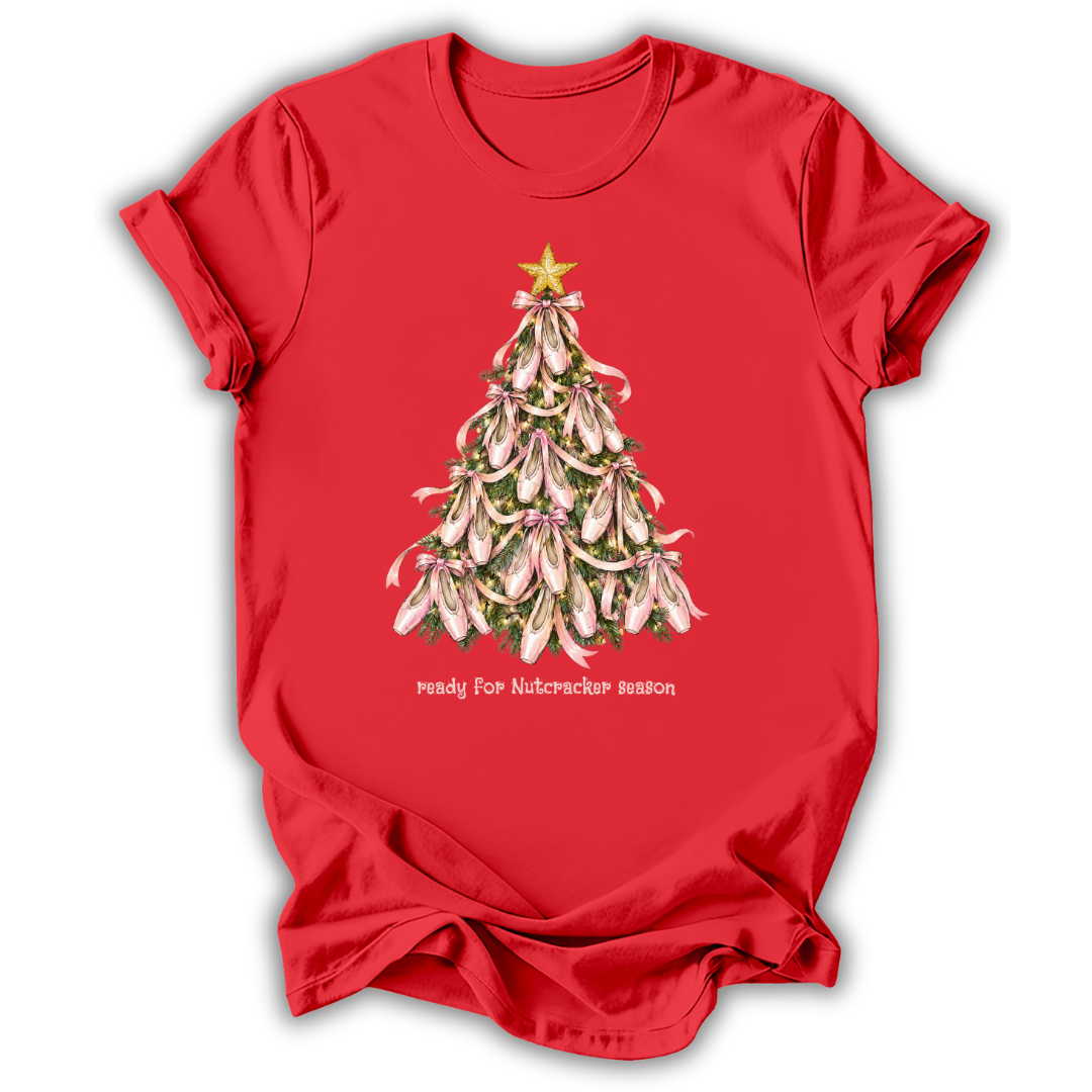 A red short-sleeve crewneck t-shirt featuring a graphic of a Christmas tree made of pink-and-white bolls flowers with a gold star on top, and the text 'ready for nutcracker season' printed below.