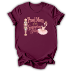 A maroon short-sleeve t-shirt with a graphic print that reads 'Proud Mom of the Sugarplum Fairy' in pink script, accompanied by illustrations of a nutcracker and a ballerina in a pink tutu, shown on a plain white background.
