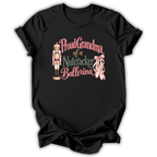 A black short-sleeve t-shirt with a graphic print that reads 'Proud Grandma of a Nutcracker Ballerina' in pink and green lettering, accompanied by an illustration of a nutcracker and pink ballet slippers.