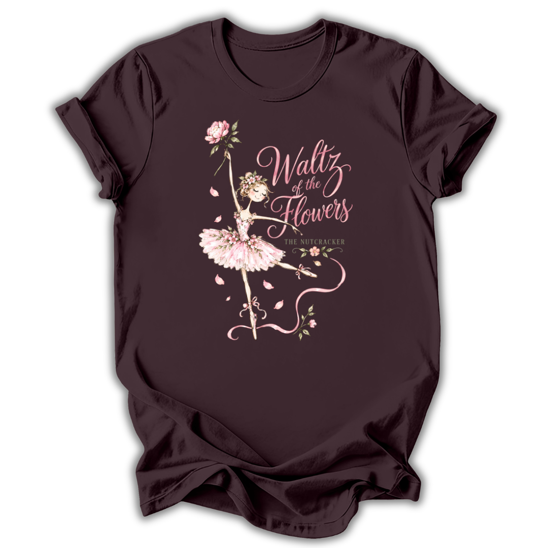 A dark plum-colored short-sleeve t-shirt with a graphic print of a ballerina in a pink tutu next to the text 'Waltz of the Flowers' and 'The North Shore'.