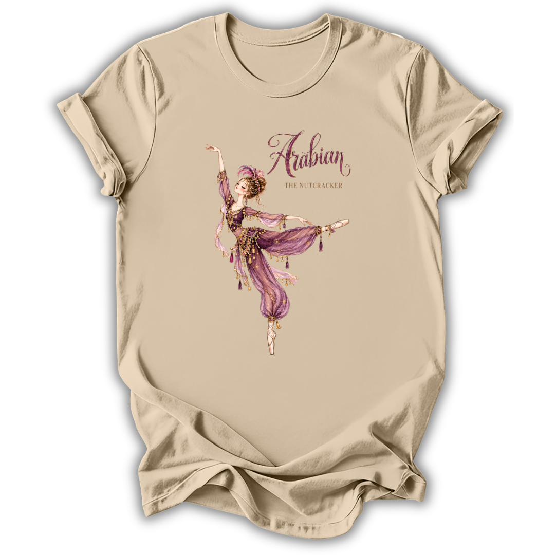 A beige short-sleeve t-shirt with a graphic print of an Arabian dancer in a purple outfit and the text 'Arabian The Nutcracker' on the front, displayed against a white background.