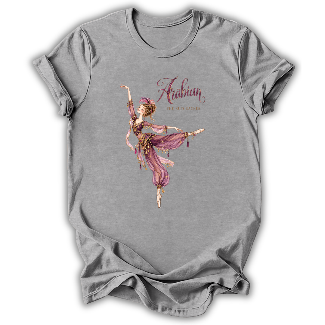 A heather gray short-sleeve t-shirt with a graphic of a dancing Arabian woman in a pink and gold outfit, with the text 'Arabian The Alchemist' printed on the front.