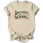 A beige short-sleeve crewneck t-shirt with a graphic print on the front. The graphic features a nutcracker soldier, pink ribbons, and the text 'Not in the Cast, Still in the CHAOS' in dark green and pink lettering.