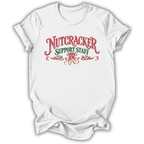 A white short-sleeve crewneck t-shirt with a festive graphic on the chest reading 'NUTCRACKER SUPPORT STAFF' in red and green lettering, decorated with candy canes and a nutcracker silhouette.