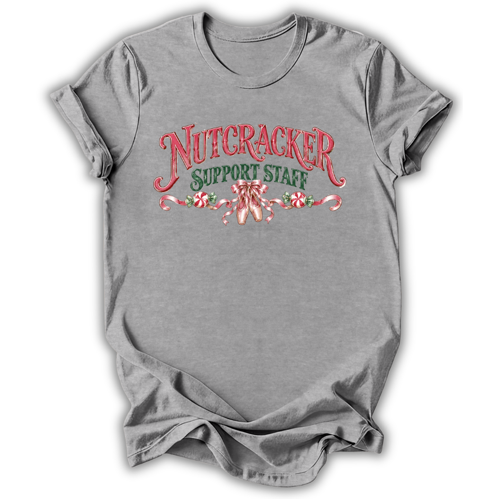 A heather gray short-sleeve t-shirt with a 'Nutcracker Sewing Club' graphic on the chest, featuring a nutcracker soldier, green script text, and a red spool of thread, shown on a white background.