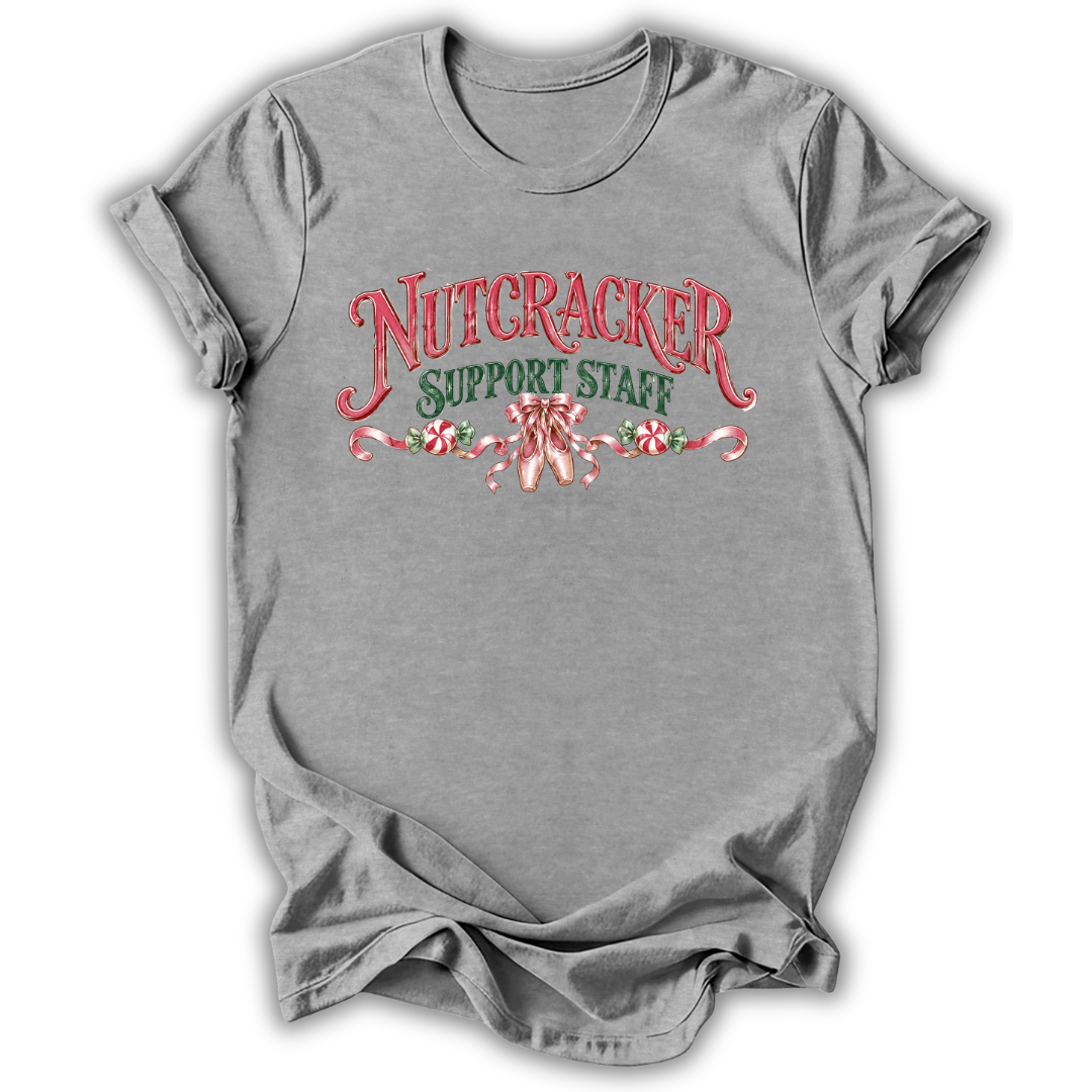 A heather gray short-sleeve t-shirt with a 'Nutcracker Sewing Club' graphic on the chest, featuring a nutcracker soldier, green script text, and a red spool of thread, shown on a white background.