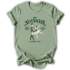 A sage green short-sleeve t-shirt with a vintage-style graphic of 'The Nutcracker' ballet, featuring a nutcracker soldier and ballerina with text detailing the Saint Petersburg premiere on December 18, 1892.