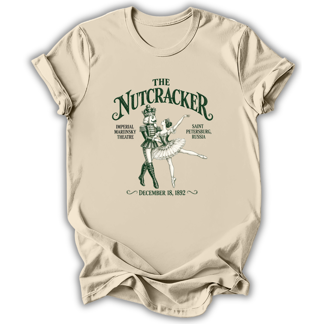 A beige short-sleeve t-shirt with a vintage-style green graphic of 'The Nutcracker' ballet dancers and text detailing the premiere in Saint Petersburg, Russia, shown on a white background.