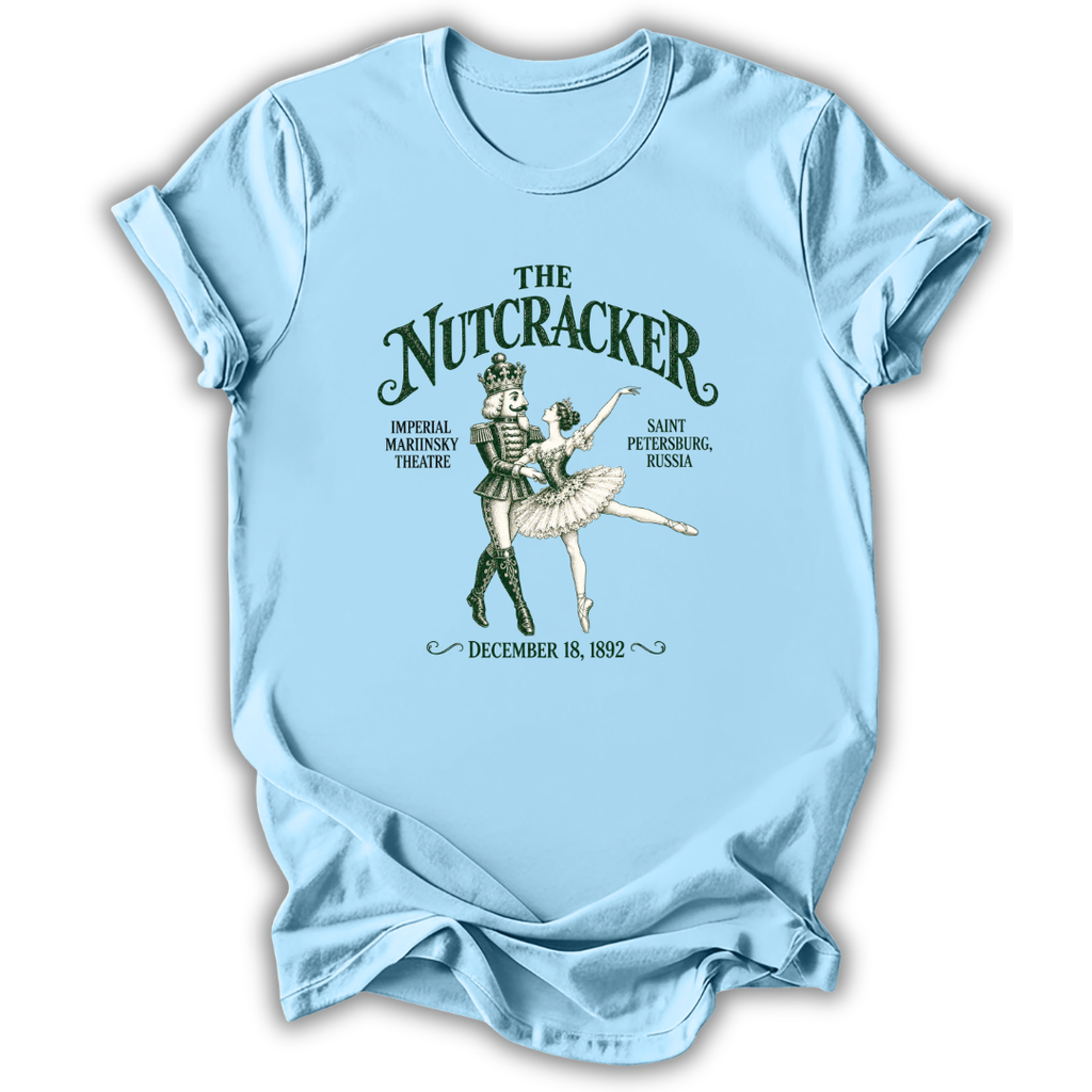 A light blue short-sleeve t-shirt with a vintage-style graphic of 'The Nutcracker' ballet, featuring a nutcracker and ballerina illustration with text details, displayed on a clean white background.