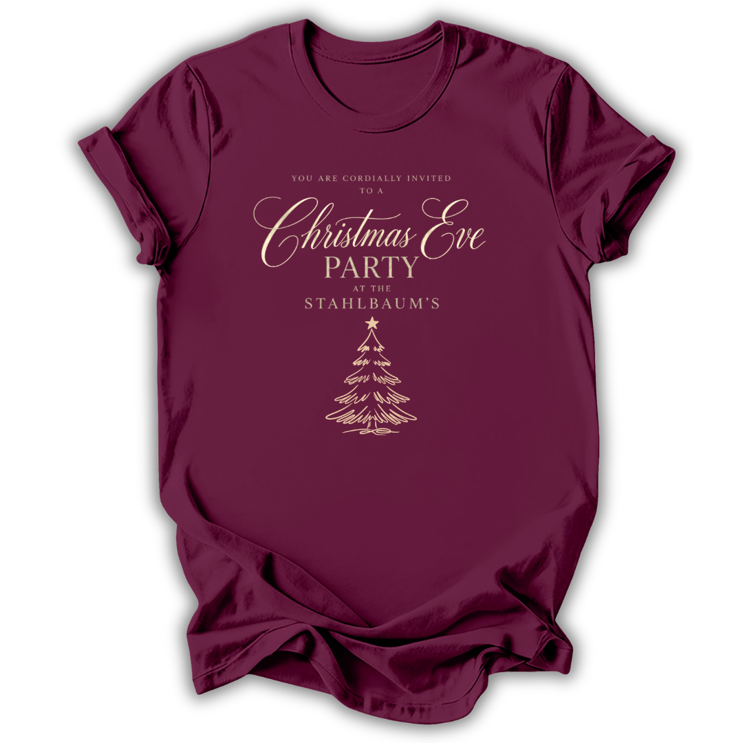 A maroon short-sleeve t-shirt with a gold printed Christmas Eve party invitation design on the front, displayed against a clean white background.