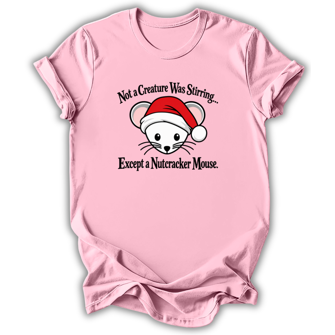 A light pink short-sleeve t-shirt with a graphic of a white nutcracker mouse wearing a red Santa hat, with the text 'Not a Creature Was Stirring.