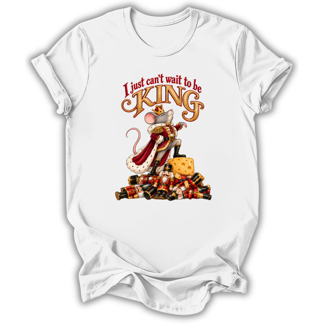 A white short-sleeve crewneck t-shirt with a graphic print of a mouse dressed as a king on a pile of candy canes, with the text 'I just can't wait to be KING' above it.