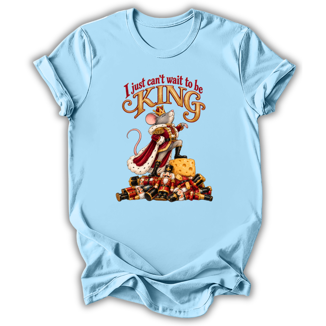 A light blue short-sleeve t-shirt with a graphic of a mouse dressed as a king on a pile of gold coins, with the text 'I just can't wait to be KING' above it.