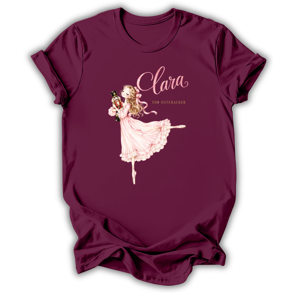 A maroon short-sleeve t-shirt with a graphic of a ballerina in a pink dress and the text 'Clara The Nutcracker' printed on the front, displayed on a clean white background.