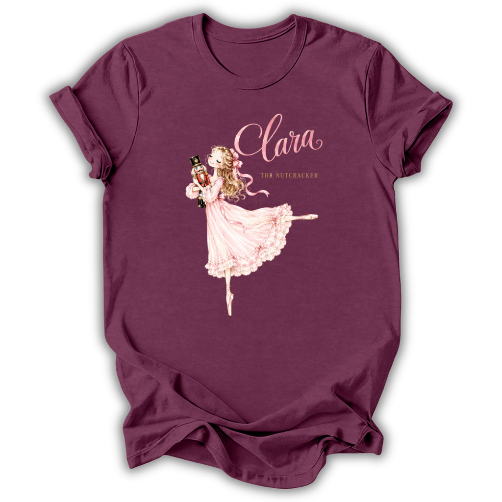 A maroon short-sleeve t-shirt with a graphic of a ballerina in a pink dress and the text 'Clara The Nutcracker' printed on the front, displayed on a clean white background.