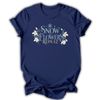 Navy short-sleeve t-shirt with a graphic on the chest that reads 'SNOW FLOWERS REPEAT' in blue and gold lettering, decorated with white snowflakes and flowers, shown on a white background.