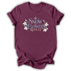 Heather maroon short-sleeve t-shirt with a graphic on the chest that reads 'SNOW FLOWERS REPEAT' in blue and gold lettering, decorated with white snowflakes and flowers, shown on a white background.