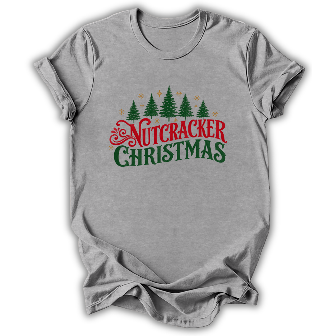 A heather gray short-sleeve t-shirt with a 'Nutcracker Christmas' graphic on the chest, featuring green pine trees and red and green text, displayed on a white background.