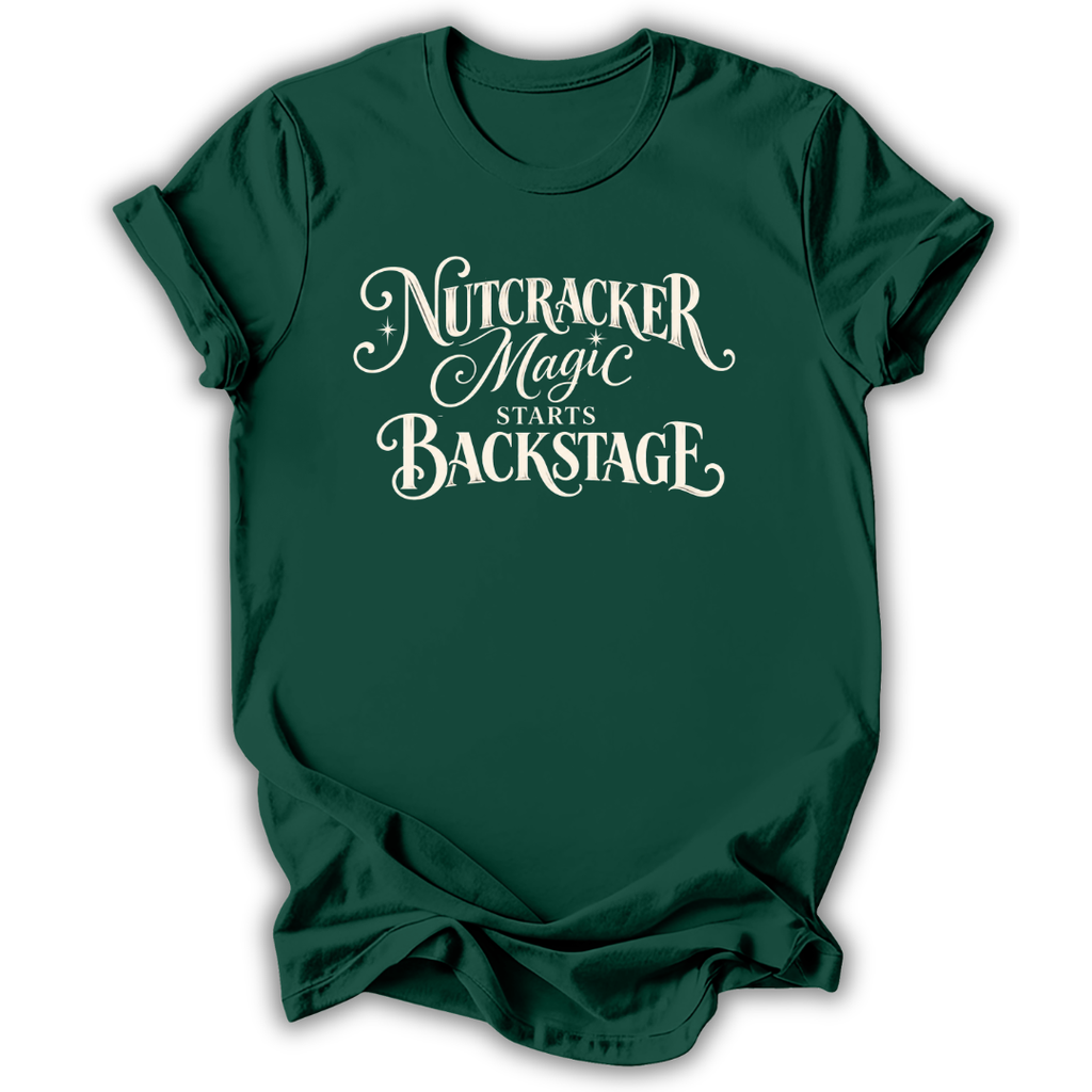 A dark green short-sleeve t-shirt with a white graphic text print reading 'Nutcracker Magic Starts Backstage' on the front, displayed against a clean white background.